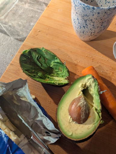 A photo of two halves of an avocado, at which someone has hacked away with a butter knife and a great deal of violence.